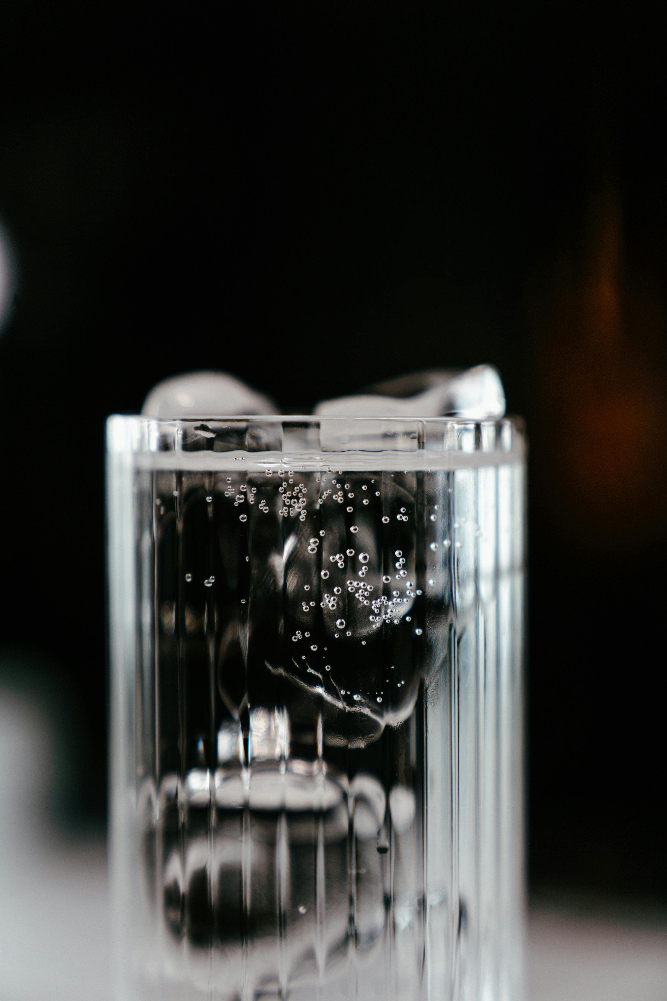 A digital thermometer showing a fever temperature next to a glass of water with ice cubes